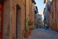 Pienza, Italy Ã¢â¬â May 27, 2017: Beautiful narrow street with sunlight and flowers in the village of Pienza, Italy Royalty Free Stock Photo